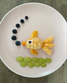 a white plate topped with an orange fish and grapes