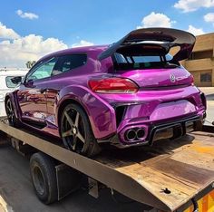 a purple sports car is on the back of a tow truck