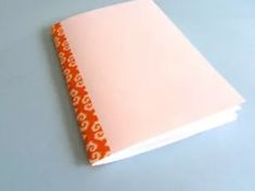 an orange and white dotted notebook sitting on top of a blue surface with the cover pulled down