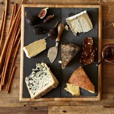 an assortment of cheeses and crackers on a wooden tray