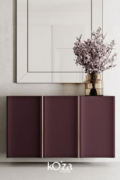 a vase filled with flowers sitting on top of a wooden cabinet next to a mirror