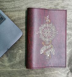 a leather notebook with an embroidered dream catcher on the cover next to a laptop computer