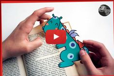 someone is holding an open book and pointing to the dragon on it's page