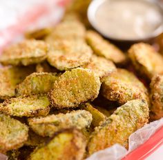 some fried food is sitting in a red bowl with dipping sauce on the side,