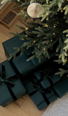 presents under the christmas tree are wrapped in dark green paper and tied with black ribbon