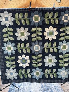 a blue and green quilt hanging on a wall