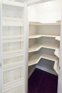 an empty walk in closet with white shelves