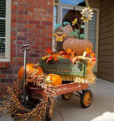 a wagon filled with pumpkins and hay sitting on the side of a brick building