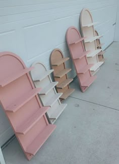 three pink and white bookshelves on the side of a garage