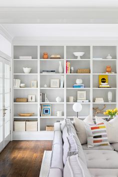 a living room filled with lots of white bookshelves