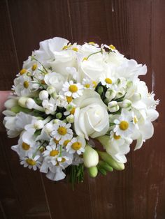 a bouquet of white flowers sitting on top of a wooden table