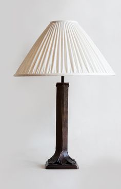 a lamp that is sitting on top of a table with a white shade over it