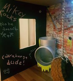 a chalkboard wall with graffiti on it next to a bucket and swing chain hanging from the ceiling