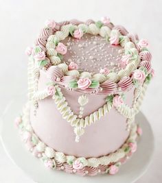 a three layer cake with pink frosting and flowers on top, sitting on a white plate