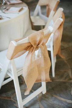 two white folding chairs with bows tied to the back are set up for a wedding reception