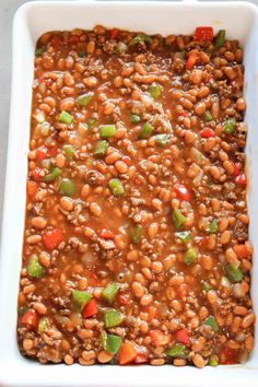 a white casserole dish filled with beans and vegetables