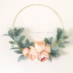 a wreath with flowers and greenery hanging on the wall