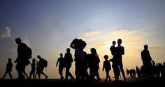 a group of people standing next to each other near the sun in the sky at sunset