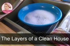 the layers of a clean house in a blue bowl on a kitchen sink with utensils next to it