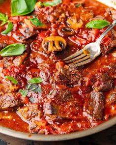 a close up of a plate of food with meat and tomato sauce