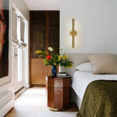 a bedroom with a bed, nightstand and painting on the wall