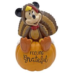 a mickey mouse figurine sitting on top of a pumpkin that says feeling grateful