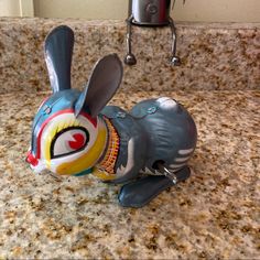 a ceramic rabbit figurine sitting on top of a counter next to a faucet