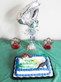 a birthday cake on a table with balloons and streamers in the shape of numbers