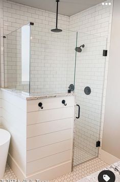 a bathroom with white tile and black hardware on the shower door, toilet and bathtub