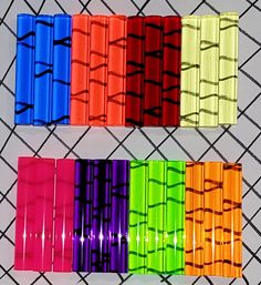 four different colors of plastic wrappers on a wire mesh fence, each with the same pattern