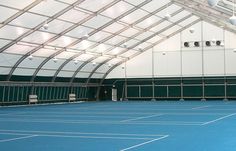 an indoor tennis court with blue tarps and white walls is seen in this image