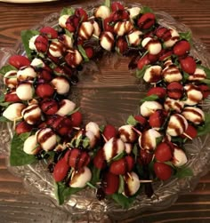 a cake that is sitting on a glass platter with fruit and leaves around it