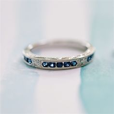 a wedding band with blue sapphire stones on the inside is sitting on a white surface