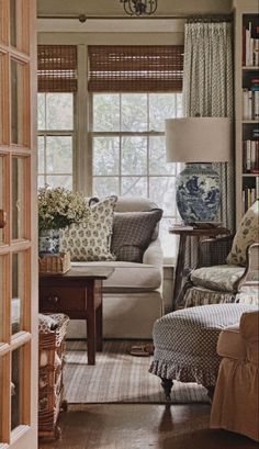 a living room filled with furniture and bookshelves next to a window covered in curtains