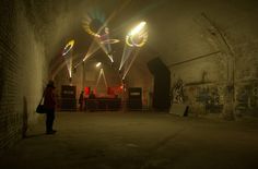 a person standing in a dark tunnel with lights on the ceiling and graffiti all over the walls