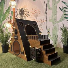 a house made out of cardboard with lights on the top and stairs leading up to it