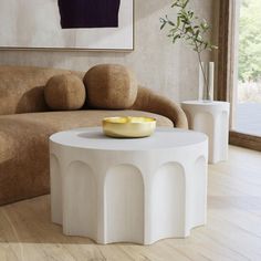 a living room with a couch, coffee table and vases on the floor in front of a painting