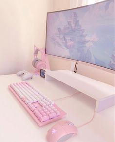 a pink computer keyboard sitting next to a mouse on top of a white desk in front of a monitor