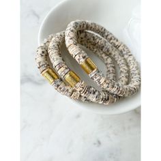 three bracelets on a white plate with gold foiled beads and two other bracelets