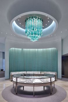 a circular glass table in the middle of a room with a chandelier hanging from it's ceiling