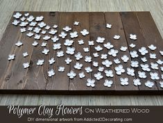 a wooden pallet with white flowers on it and the words polymer clay flowers on weathered wood