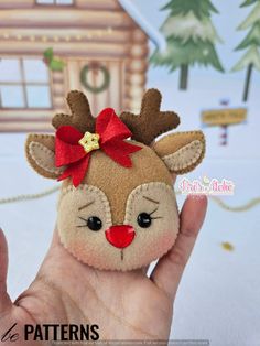 a hand holding a small stuffed animal with a red bow on it's head