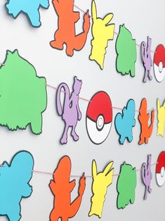 paper cut outs are hanging on a wall with pokemon symbols attached to the side of it