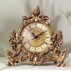 an ornate gold clock on a white table