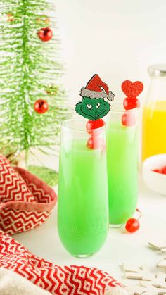 two glasses filled with green liquid next to a christmas tree and other holiday decorations on the table