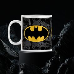 a batman mug sitting on top of a black and white table next to some rocks