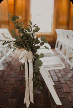 a bouquet of flowers sitting on top of a wooden table next to white folding chairs