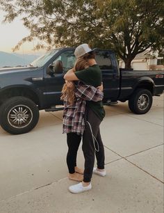 two people hugging each other in front of a truck