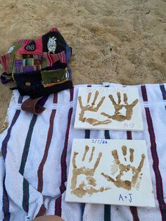 two handprints are placed on a towel next to a bag and purse, which is sitting on the beach