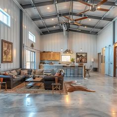 a large open living room with couches and tables in the center, surrounded by metal walls